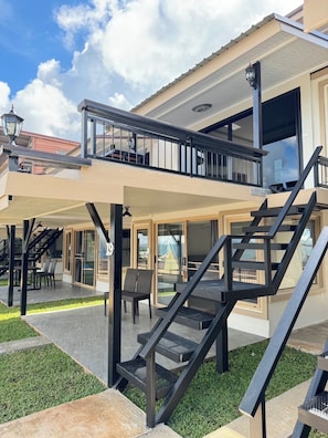 A two-story building with a balcony, outdoor seating, and a staircase.