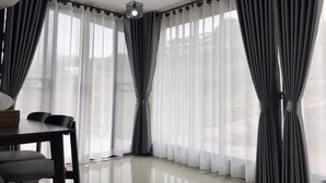 A modern room with a dining area, large windows with sheer curtains, and a ceiling light fixture. - Mon Ing Dao (Mae Rim)