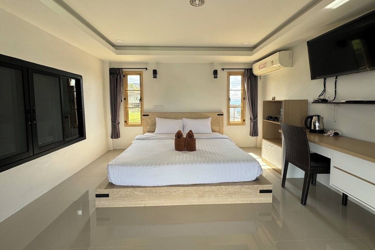 A hotel room with a bed, a desk, a television, and a window.