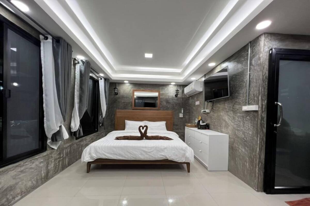 A modern bedroom with a bed, bedside table, TV, and a wardrobe.