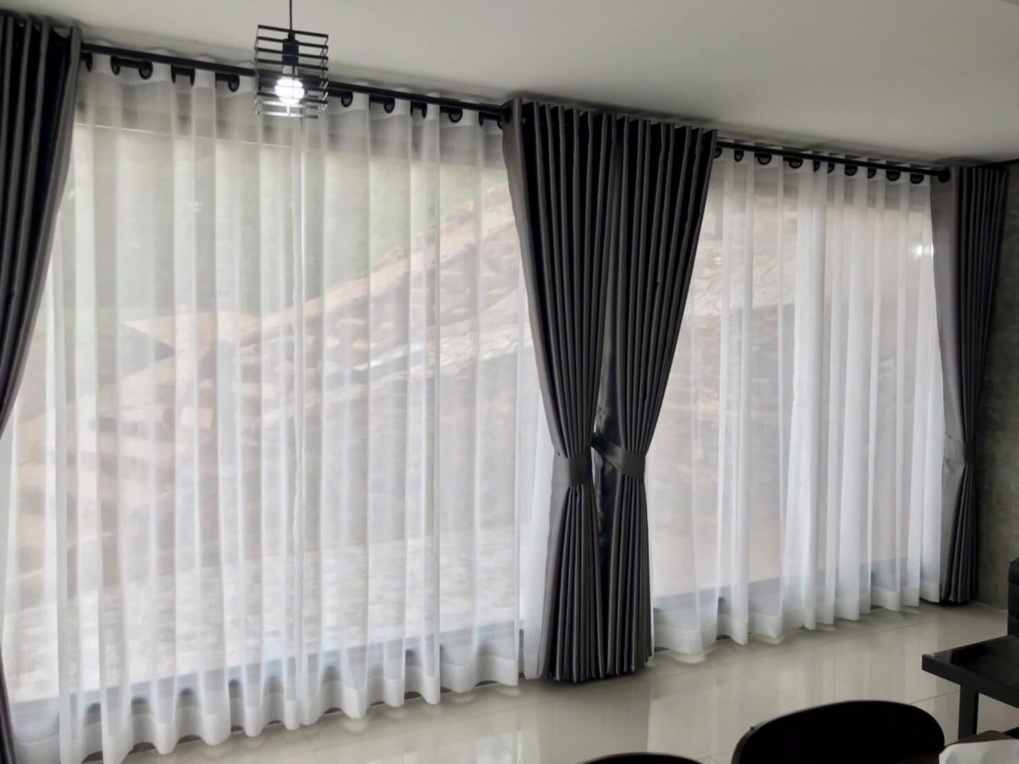 A room with a large window, a ceiling light fixture, and a chair.