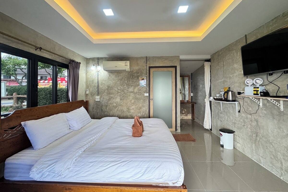 A hotel room with a bed, a TV, a bathroom, and a view of the outside.
