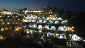 A series of dome-shaped accommodations with exterior lighting, arranged in rows on a hillside. - Mon Ing Dao (Mae Rim)