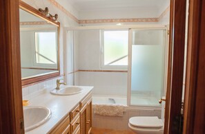 A bathroom with two sinks, a bathtub, and a toilet.