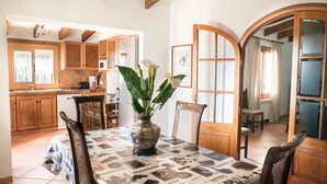 A dining area with a table set for four, surrounded by wooden chairs. A vase with white flowers is placed on the table. - SINGLE FAMILY HOUSE ISOLATED WITH POOL, RURAL HOUSE IN A LAND OF 35. 000M2 (Selva- Cami Selva- Mallorca)
