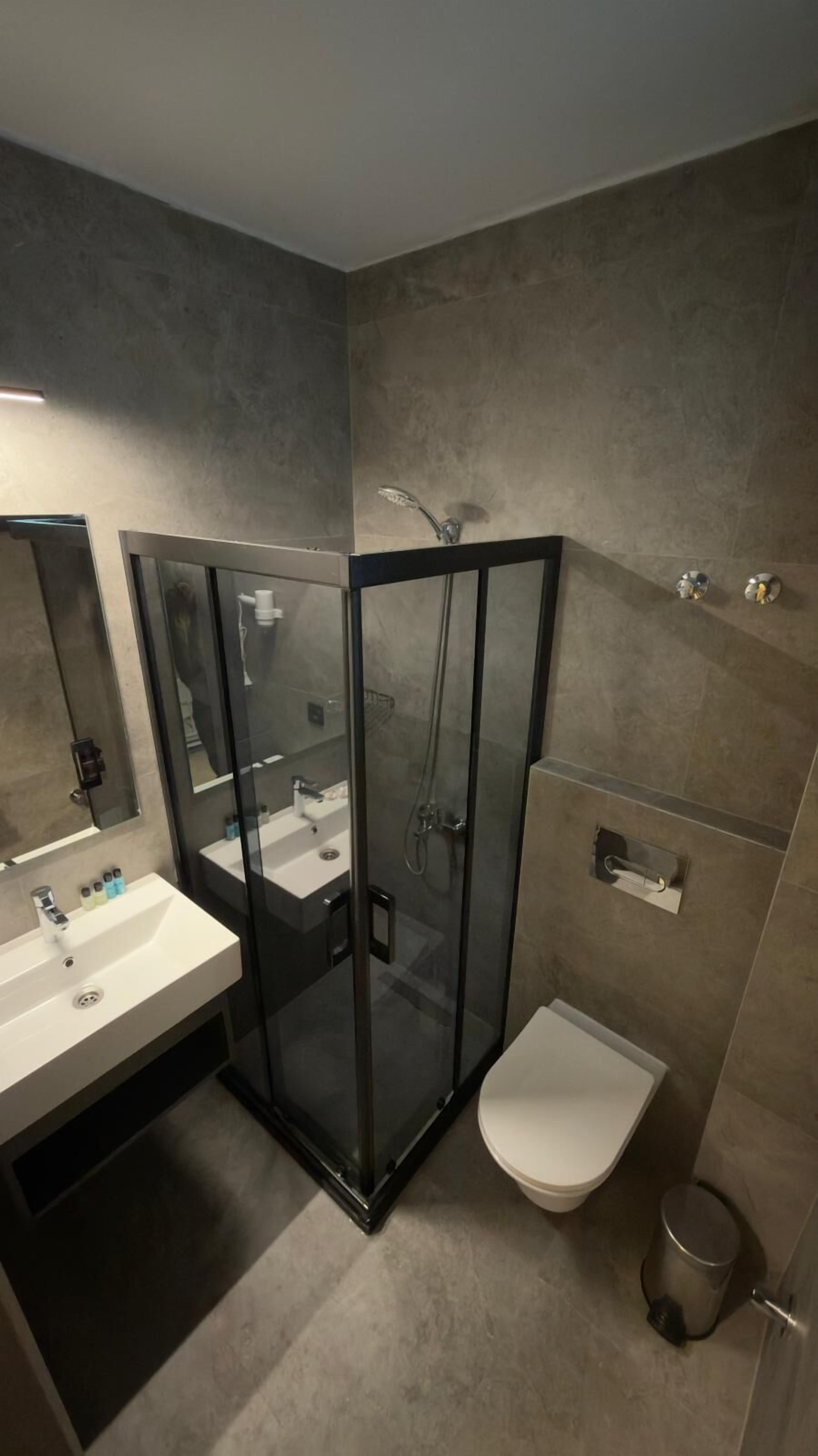 Un baño moderno con ducha acristalada, lavabo blanco y retrete.