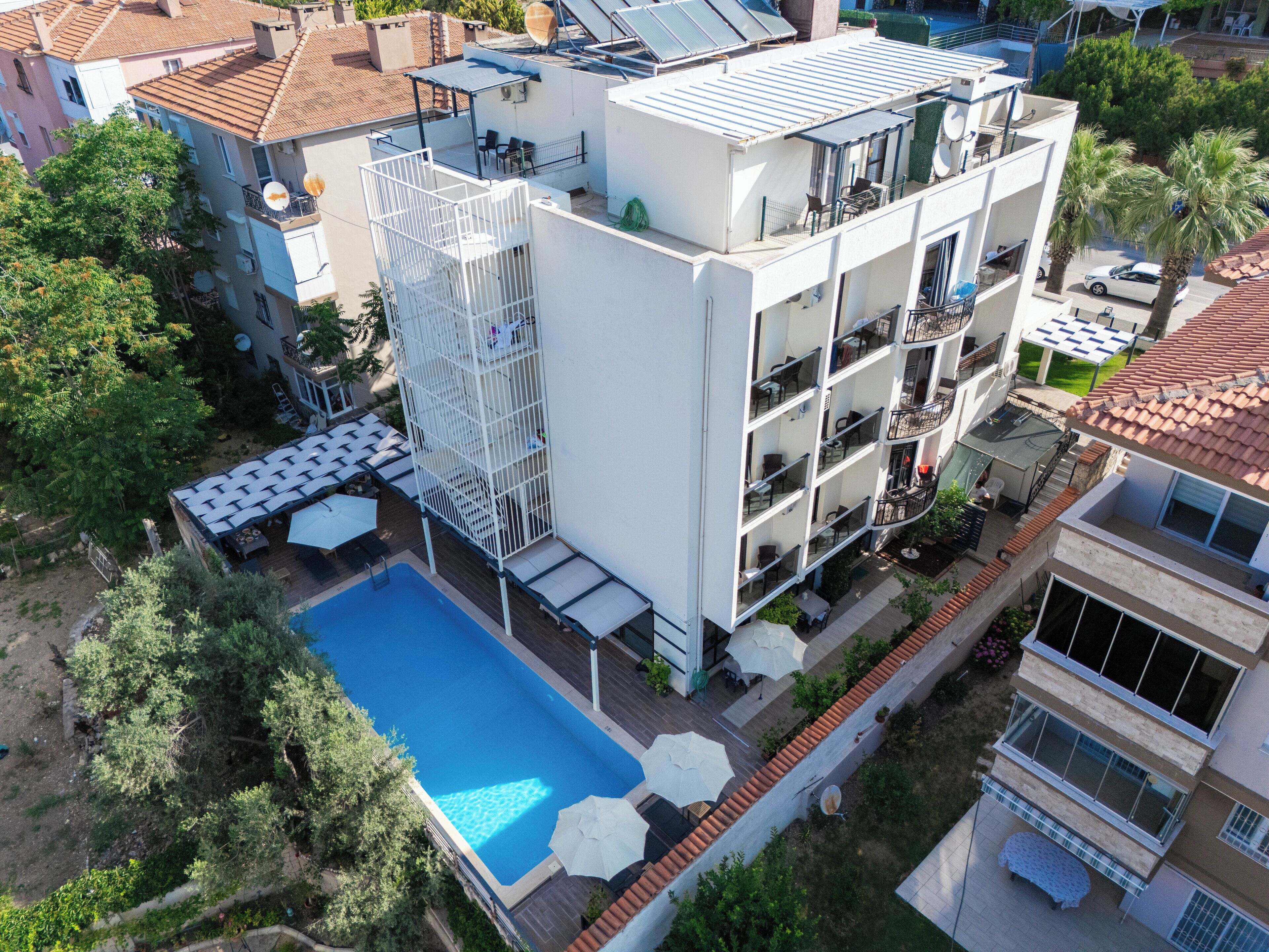A modern building with a rooftop pool, multiple balconies, and a covered outdoor seating area.