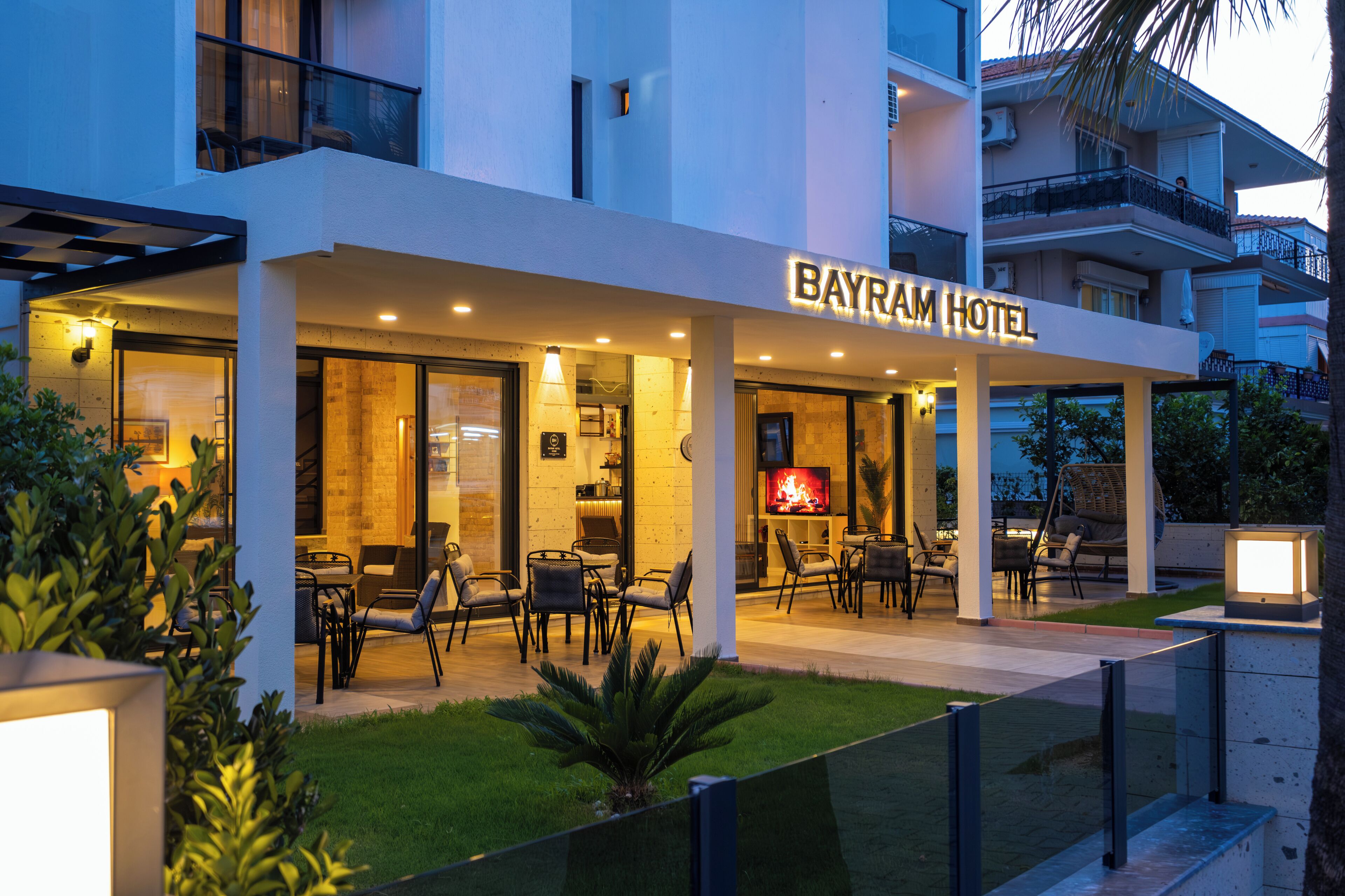 A modern hotel with a well-lit outdoor seating area and a visible TV screen.