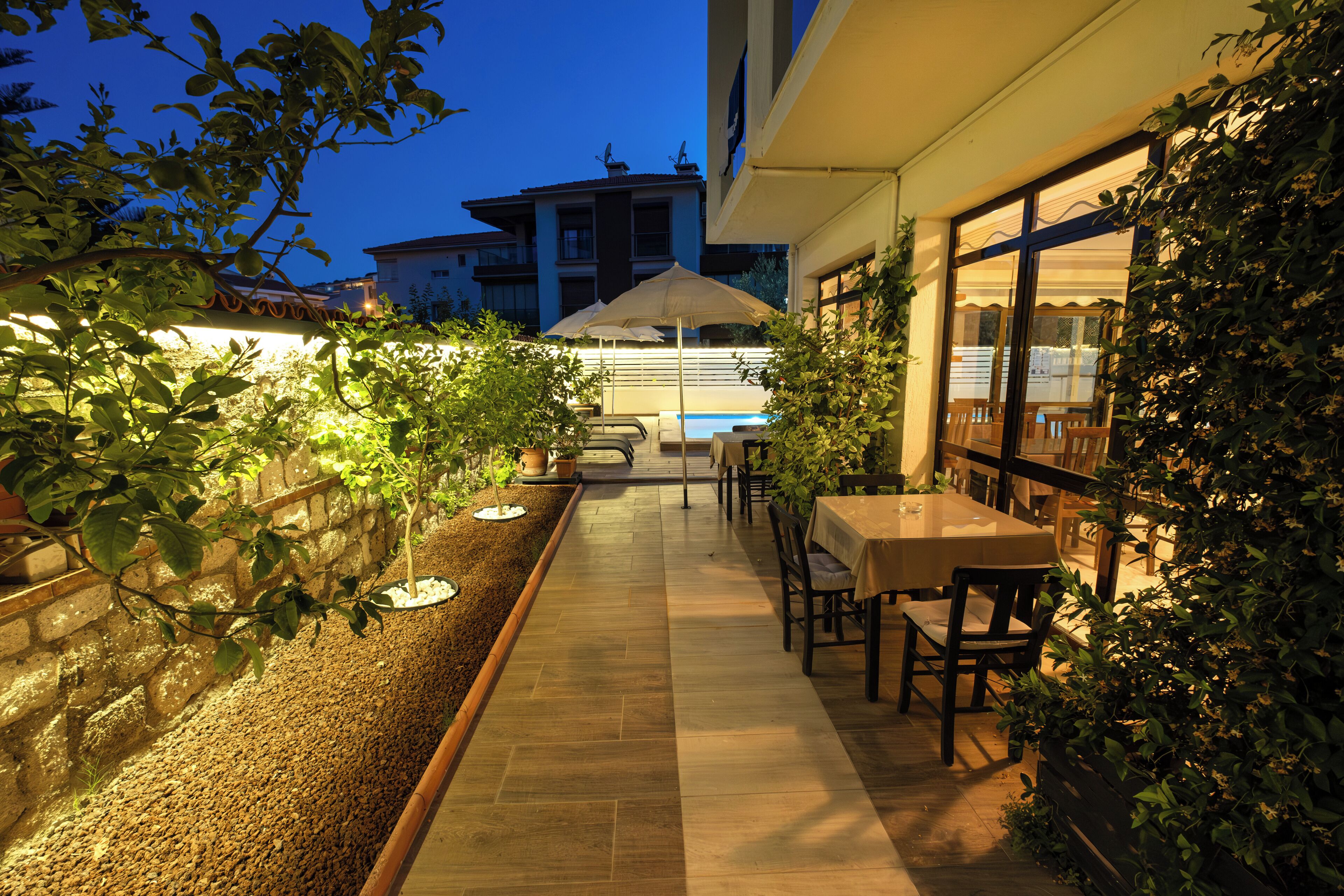 Un patio al aire libre con piscina, mobiliario y vista del edificio al fondo.