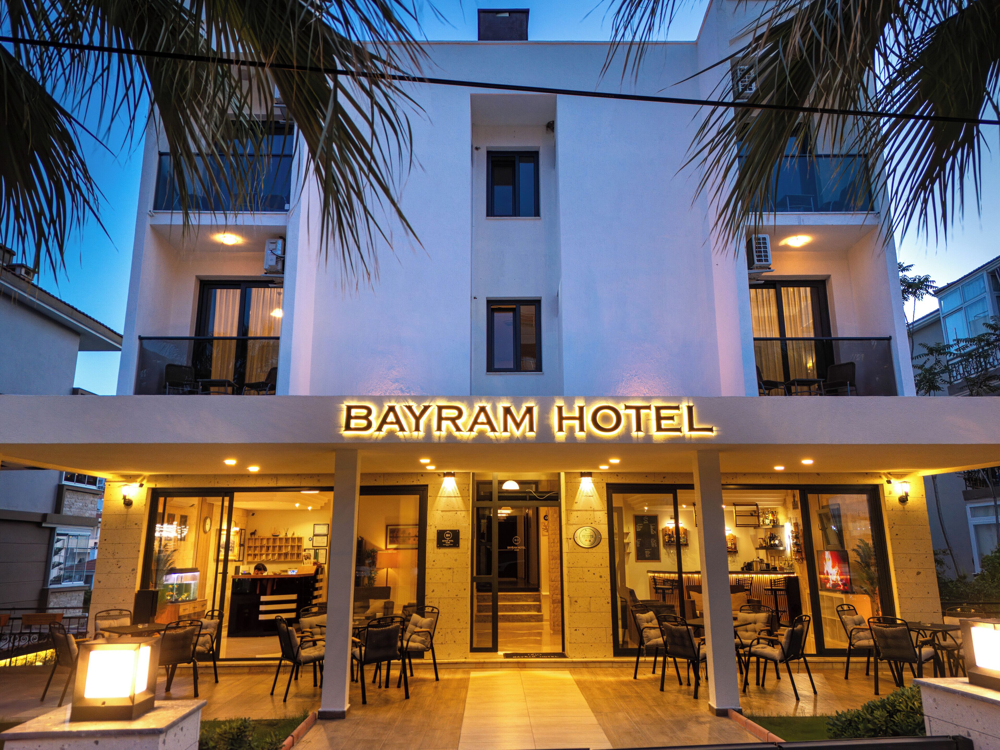 The exterior of Bayram Hotel with a well-lit entrance, outdoor seating area, and a visible bar area.