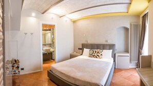 A modern hotel room with a large bed, a bedside table, a nightstand, a mirror, and a bathroom visible through an open door. - Casa Turrisi (Taormina)