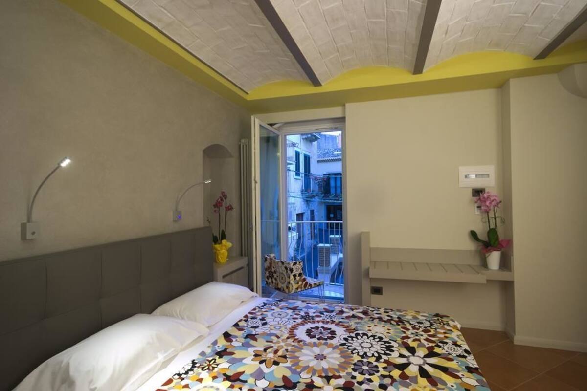 A bedroom with a bed, a window, and a door leading to a balcony.
