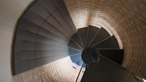 A spiral staircase with a brick wall and a dark floor. - Casa Turrisi (Taormina)