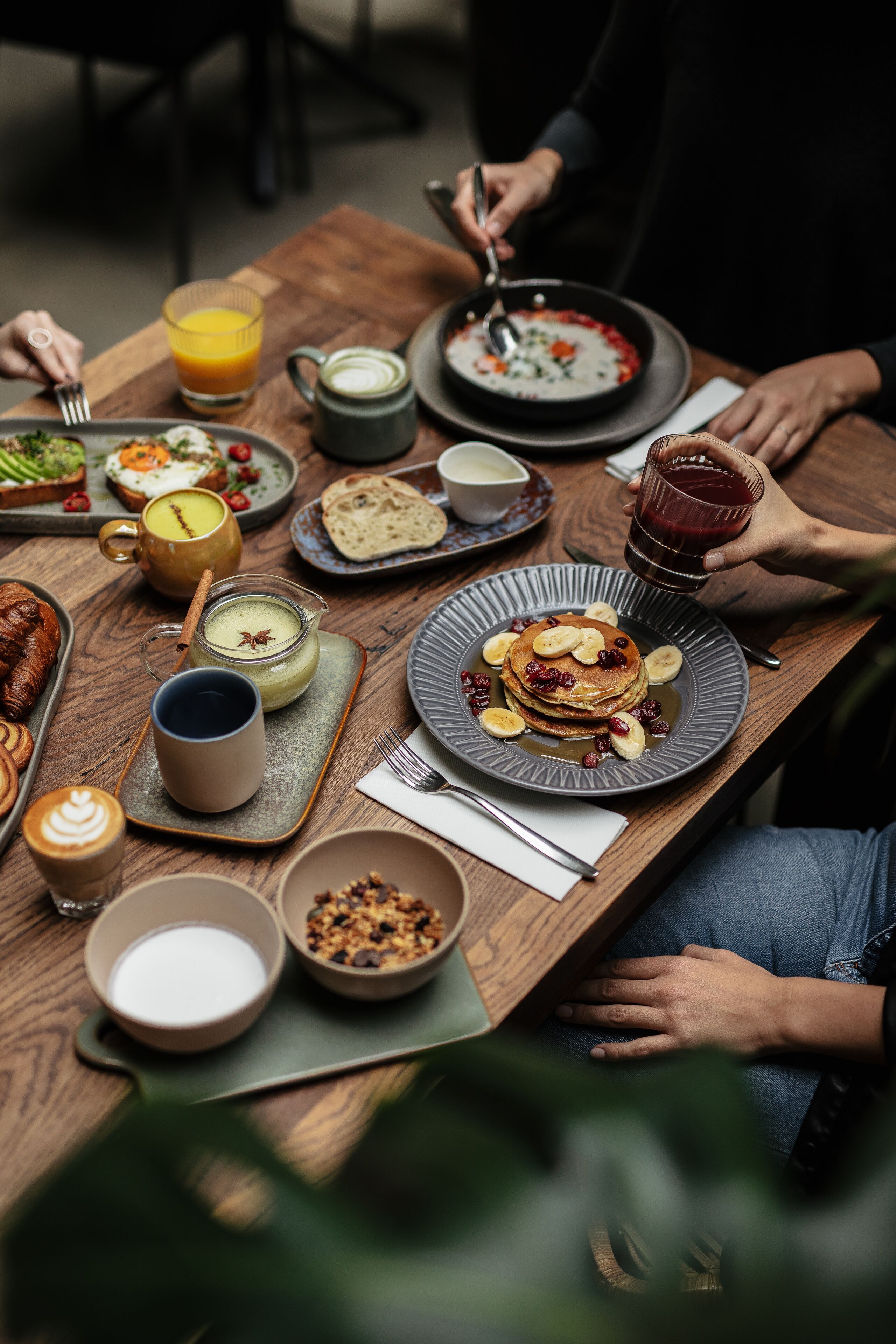 A breakfast setting with various dishes, including pancakes, a coffee cup, and a glass of orange juice.