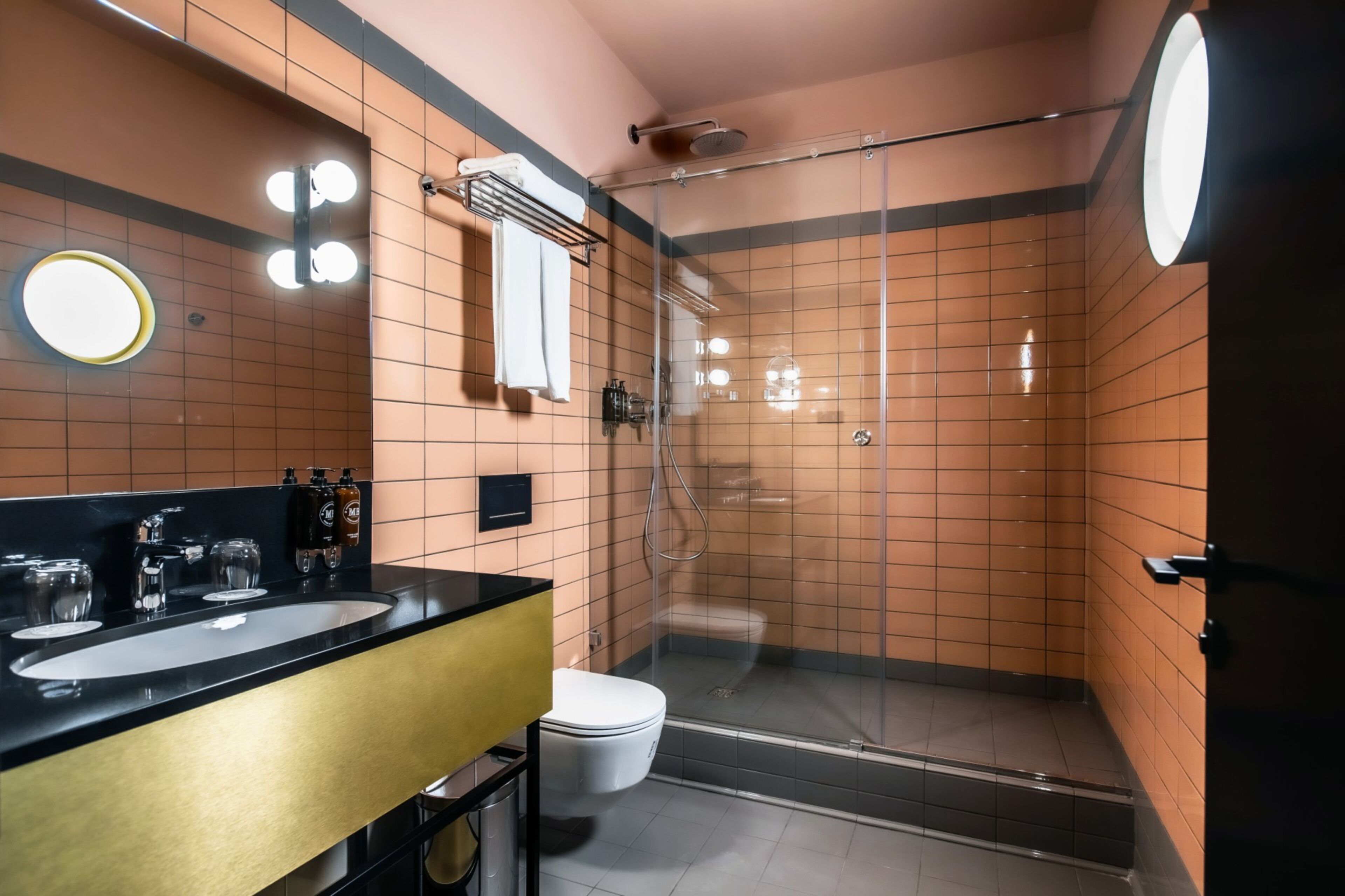 A modern bathroom with a black sink, two mirrors, a glass shower enclosure, and a toilet.