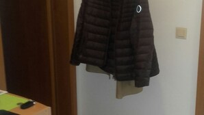 A room with a coat rack holding a dark jacket, a wooden door, and a tiled floor. - Ferienwohnung Wittelsbacherstr. 10 -  in ruhiger und zentraler Lage (Bad Reichenhall)