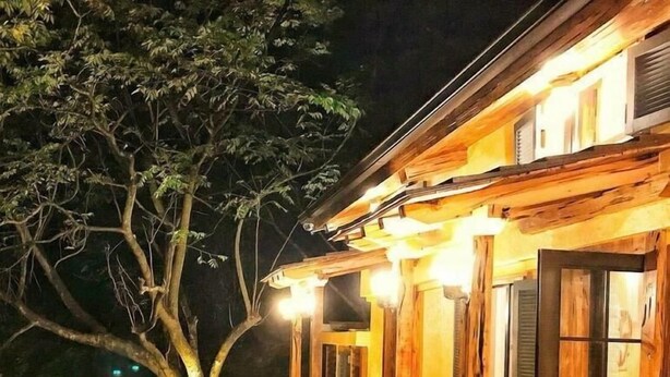 Un bâtiment en bois doté d’un porche, d’un banc et d’un arbre.