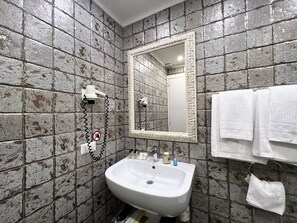 Casa de banho com lavatório branco, espelho e porta-toalhas.