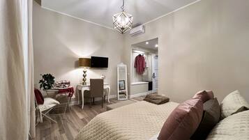 Un dormitorio con cama, mesita de noche, lámpara, silla, televisor y espejo.