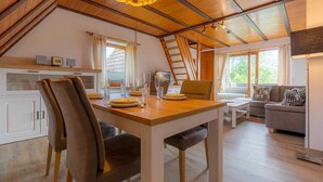 A cozy loft-style living space with a dining area, kitchen, and seating area. - Apartment 5 "Bellmann" (ID 024) - House Dorfstraße 30a (Sankt Peter-Ording)