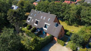 A residential house with a sloped roof, multiple skylights, and a well-maintained garden. - Apartment 5 "Bellmann" (ID 024) - House Dorfstraße 30a (Sankt Peter-Ording)