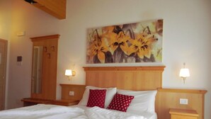 A bedroom with a large bed, two bedside tables, a wooden headboard, and a painting of flowers on the wall. - Agritur Sole Levante (Male)