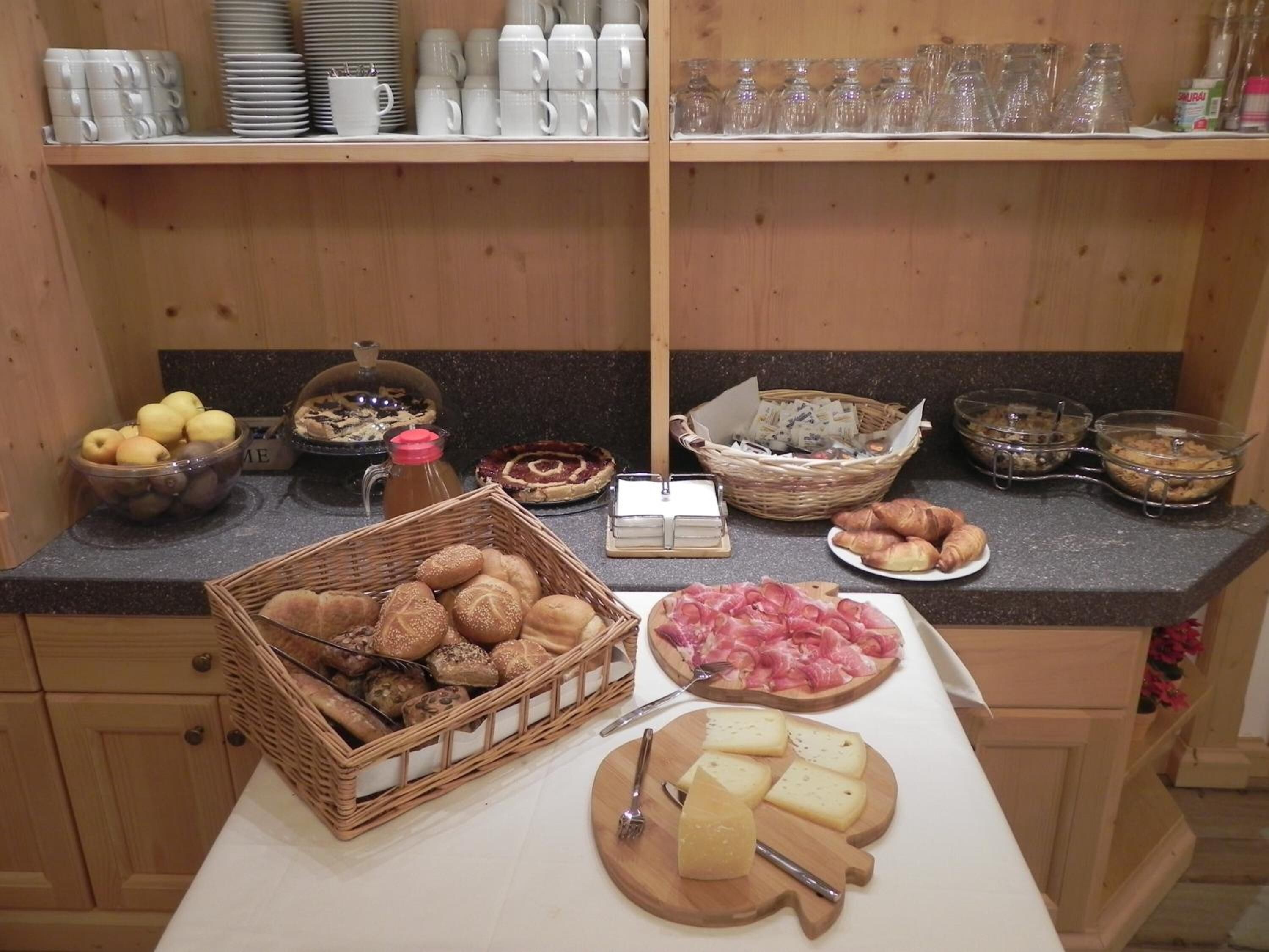 Un aparador bufet amb diversos aliments, com ara pa, formatge i pastissos.
