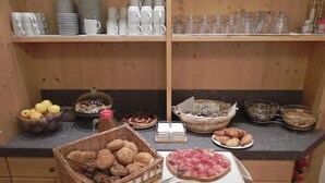 A buffet setup with various food items, including bread, cheese, and pastries, on a wooden counter. - Agritur Sole Levante (Male)