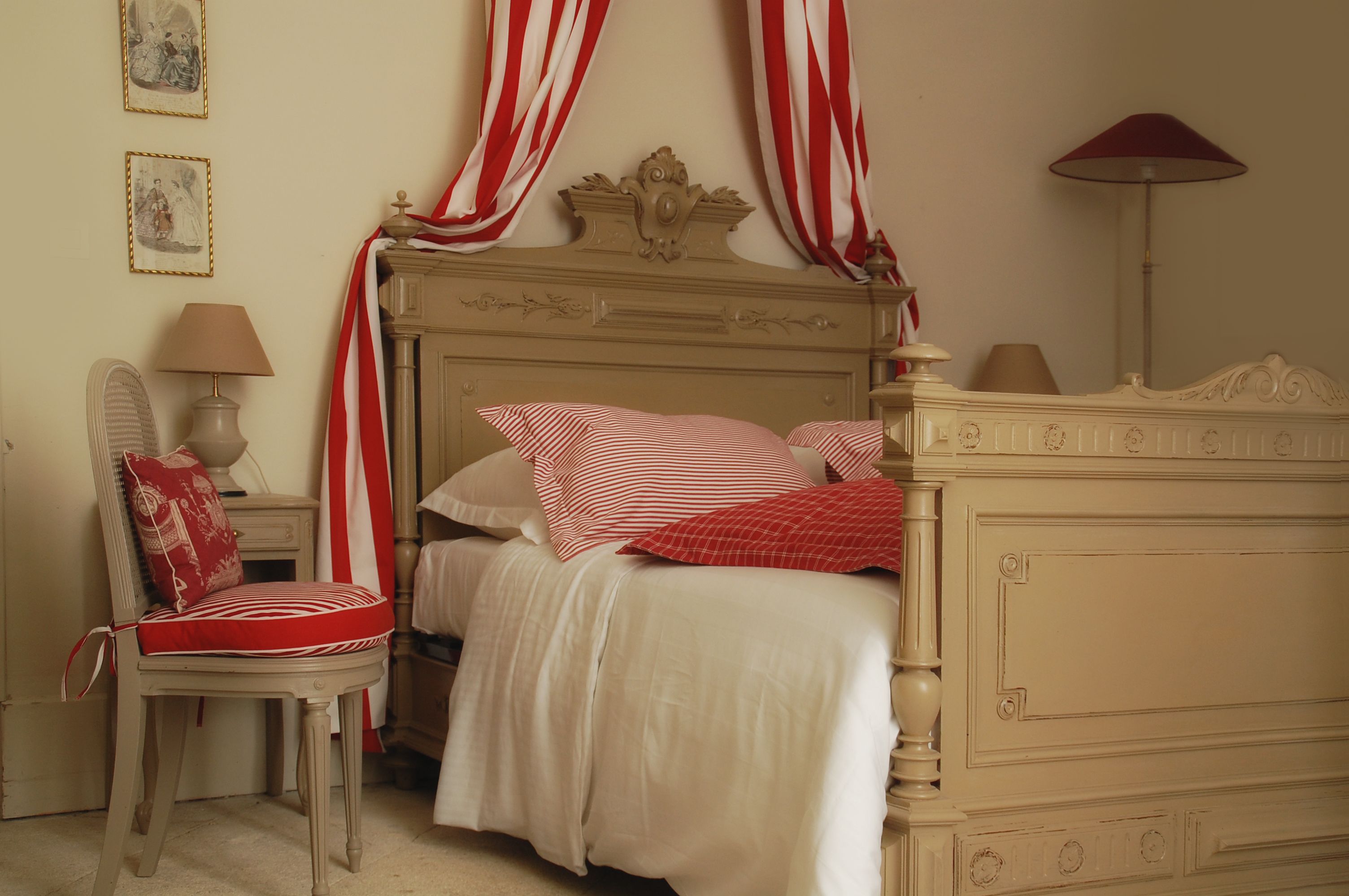 A bedroom with a bed, a chair, a lamp, and curtains.
