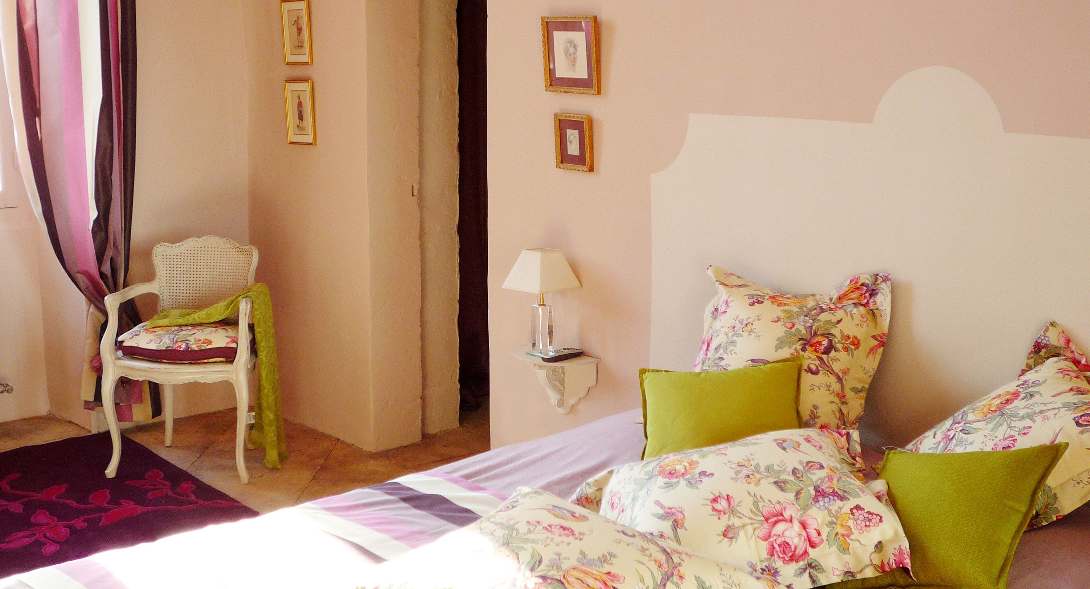 Une chambre à coucher avec un lit, une literie à motifs floraux, une chaise et une table de chevet avec une lampe.