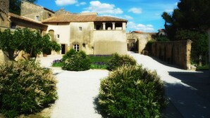 A historic building with a courtyard, stone walls, and traditional architecture. - Domaine des Escaunes (Sernhac)