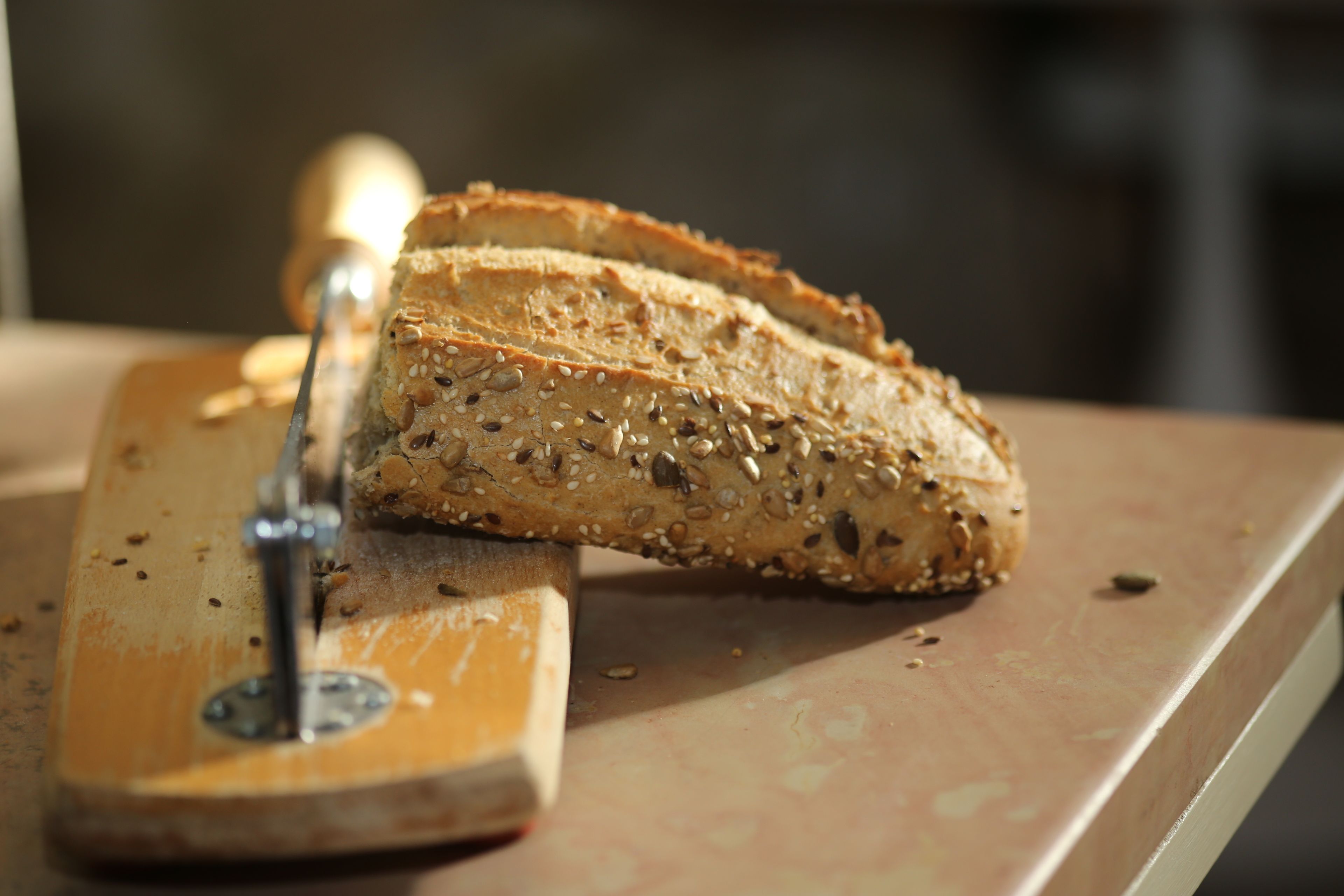 Een meergranenbrood dat op een houten snijplank wordt gesneden.