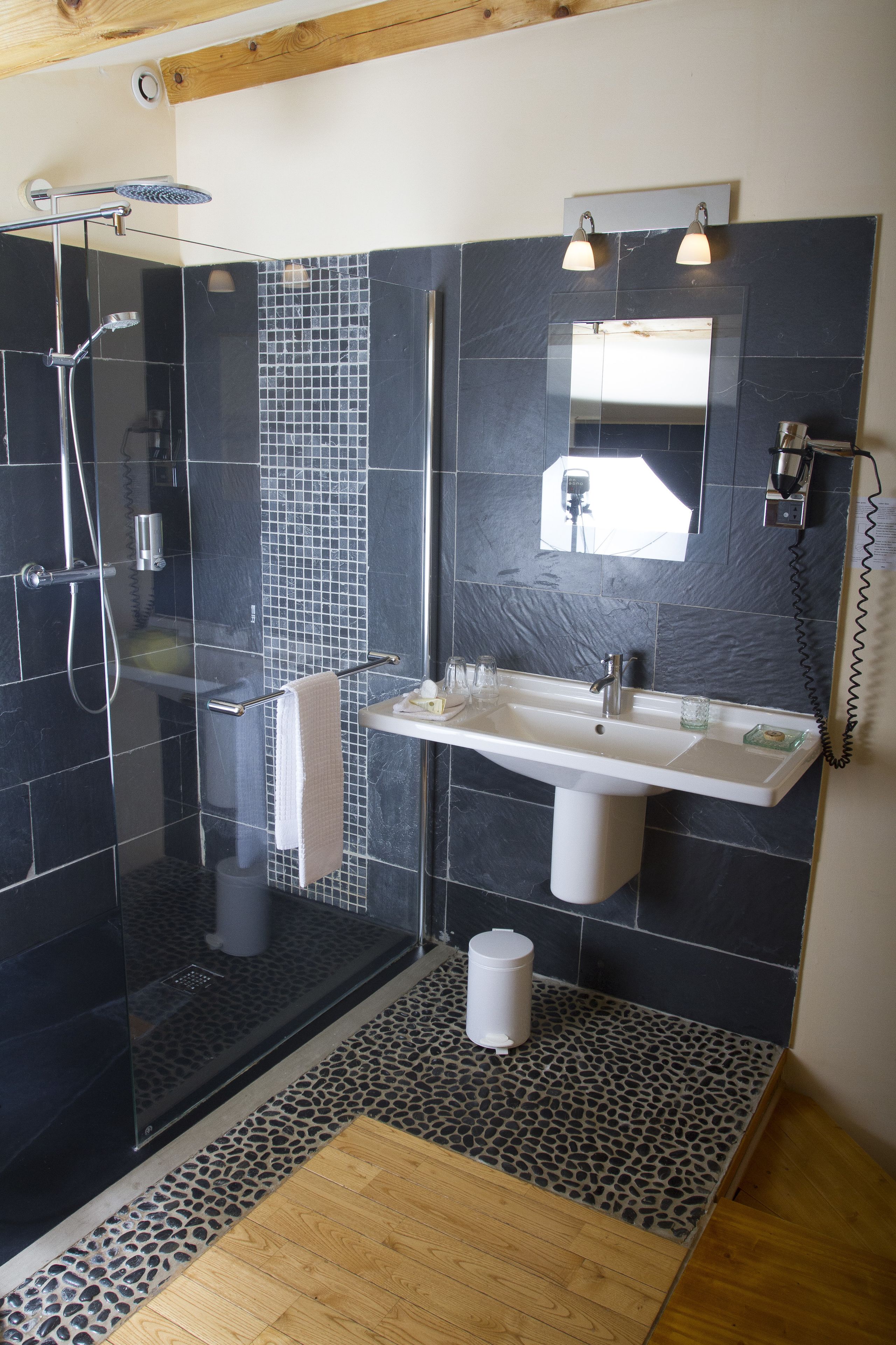 Un baño moderno con ducha envuelta en vidrio, un lavabo blanco y un espejo encima.