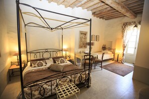 Un lit à baldaquin avec une tête de lit en bois, un bureau avec une chaise et une fenêtre avec des rideaux.