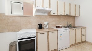 Une cuisine compacte équipée d’une cuisinière, d’un four, d’une machine à café et d’un lave-vaisselle.