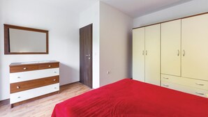 Une chambre à coucher avec un lit, une armoire, une commode et un miroir.