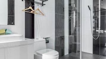 Un bagno moderno con un water bianco, una doccia con pareti in vetro e un lavandino bianco con un porta asciugamani sopra.