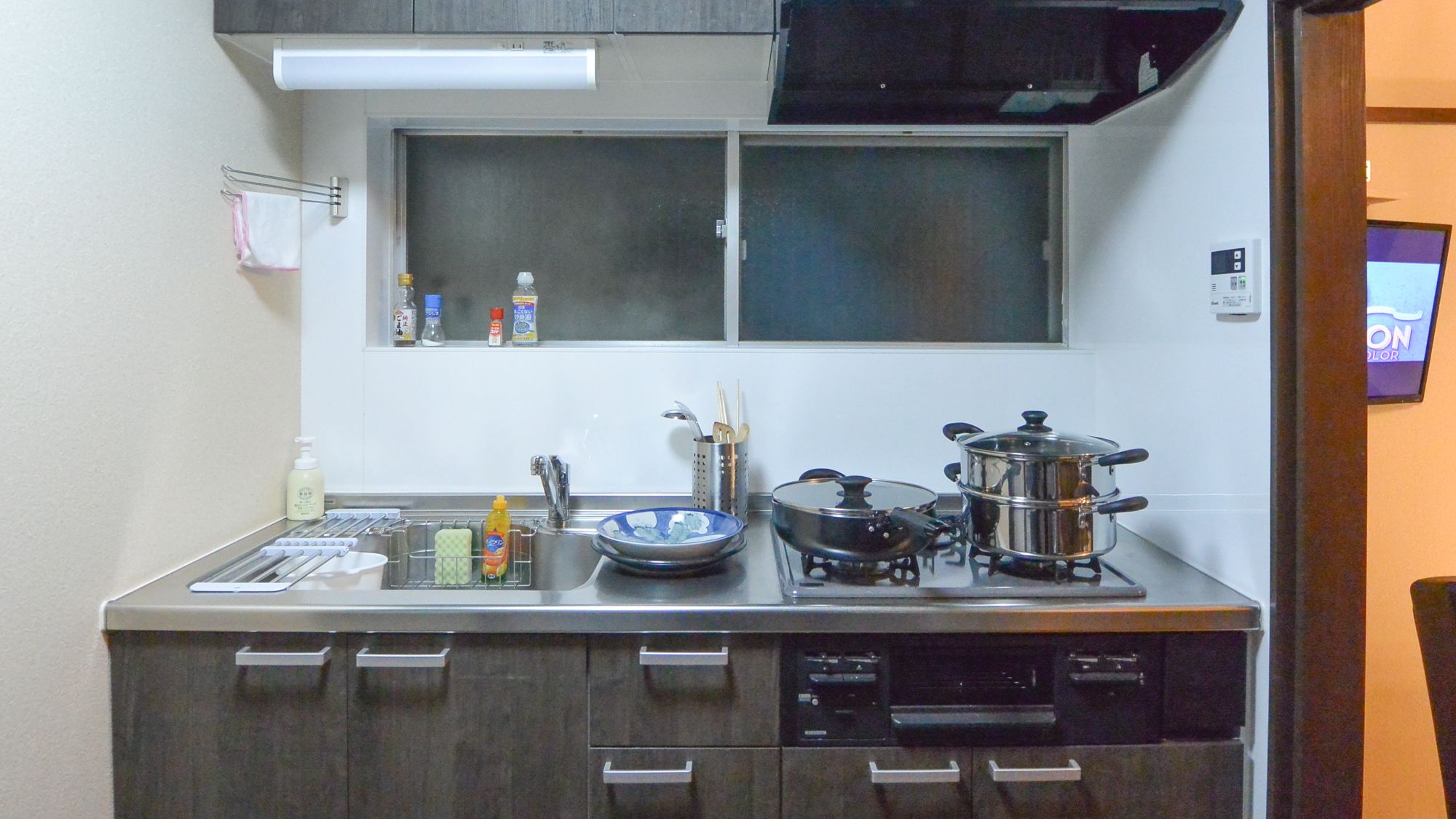 A compact kitchen with a gas stove, a sink, and a window above the countertop.