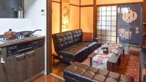 Ein kompakter Wohnbereich mit Küchenzeile, einer Couch, einem Couchtisch und einer Tatami-Matte.