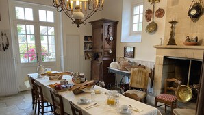 A dining room with a long table set for breakfast, surrounded by wooden chairs.
