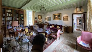 A spacious living room with a high ceiling, a fireplace, and a large window.