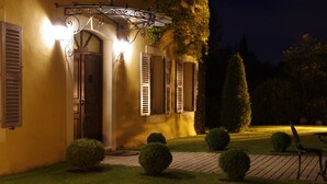 A building with a yellow facade, shutters, and a well-lit entrance.