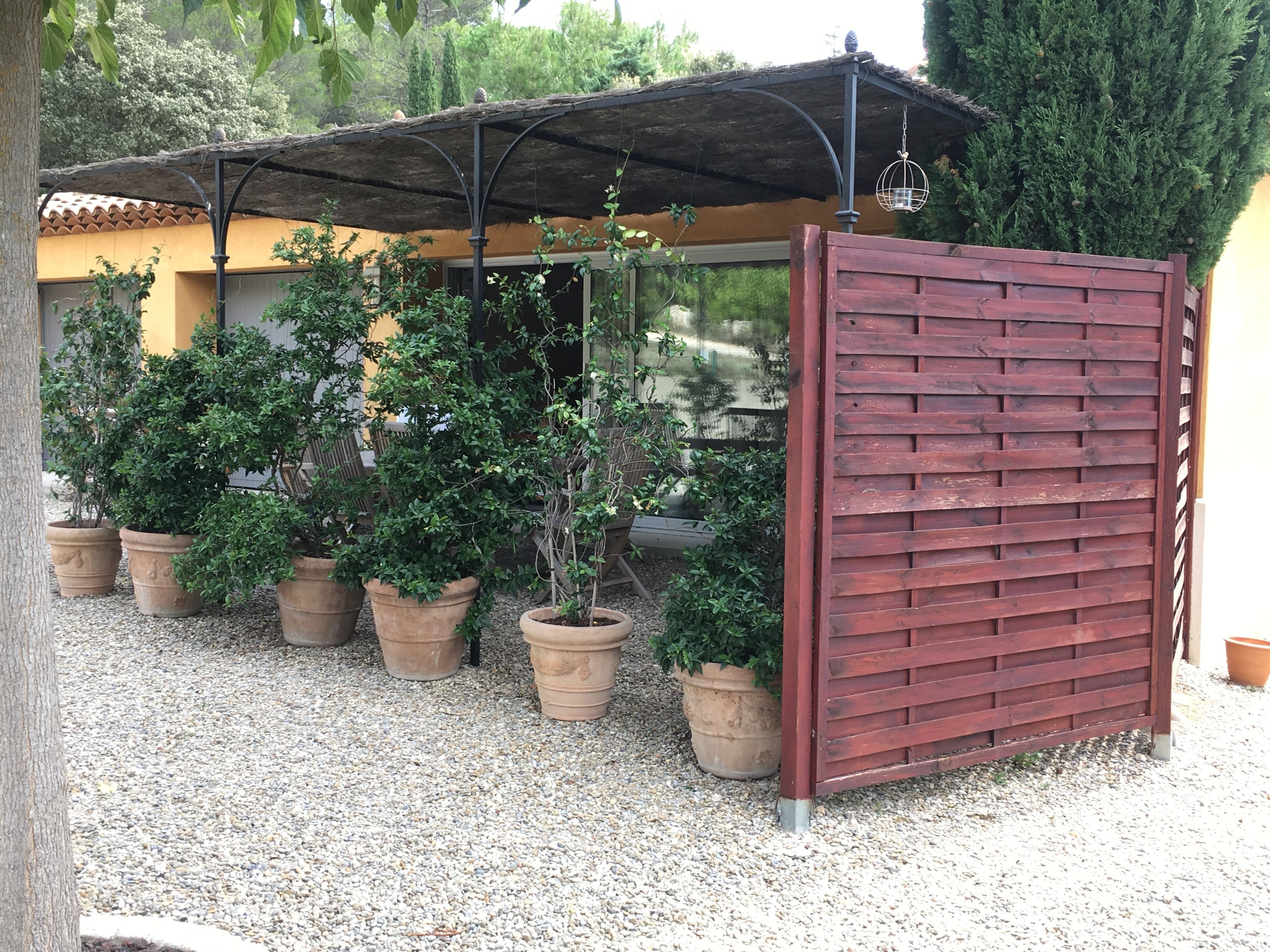 Un espacio al aire libre cubierto, con plantas en macetas y una valla de madera.