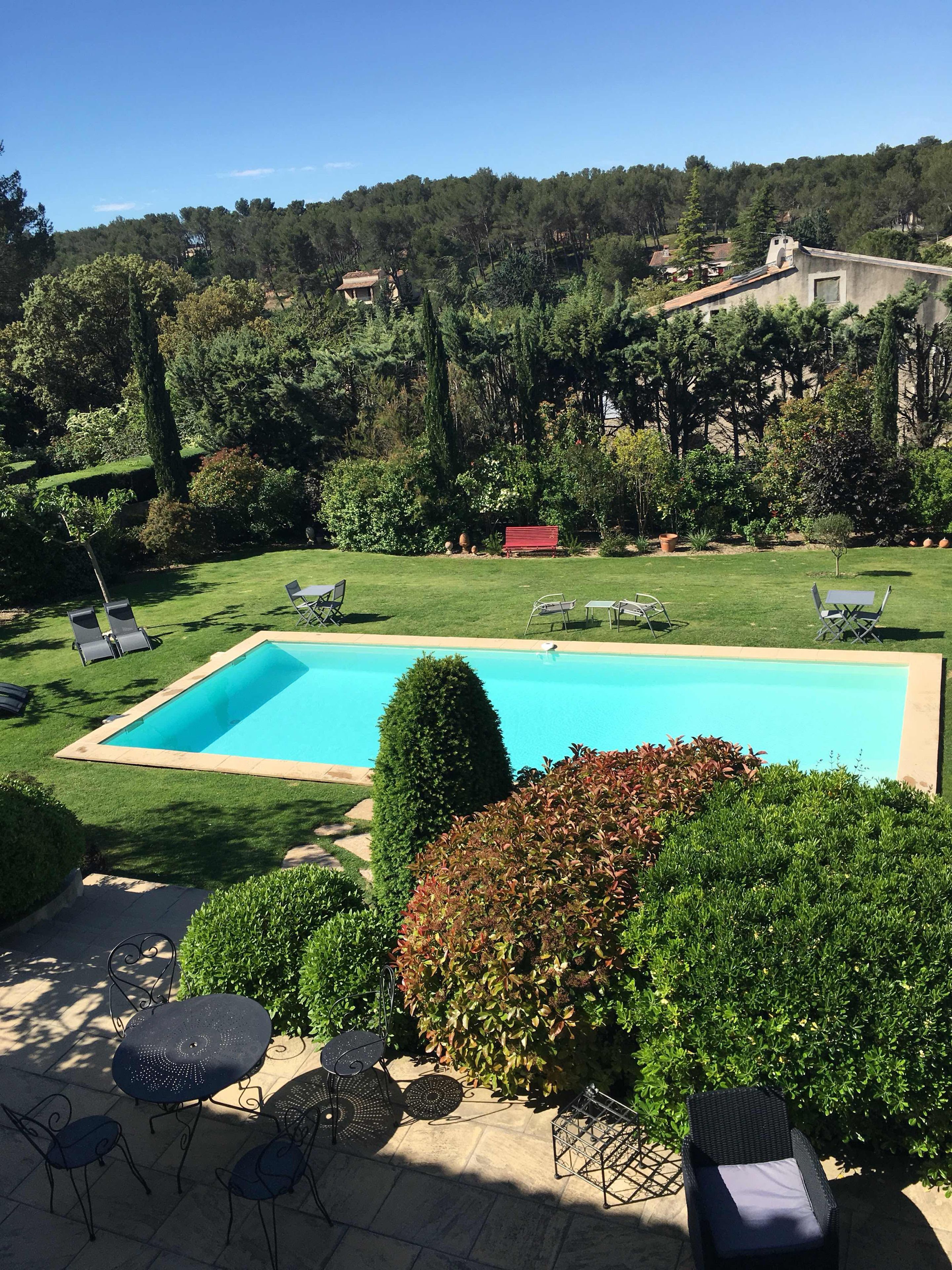Ein rechteckiger Swimmingpool, umgeben von einem gepflegten Rasen, mit mehreren Liegestühlen und einer Terrassen-Sitzgelegenheit im Vordergrund.