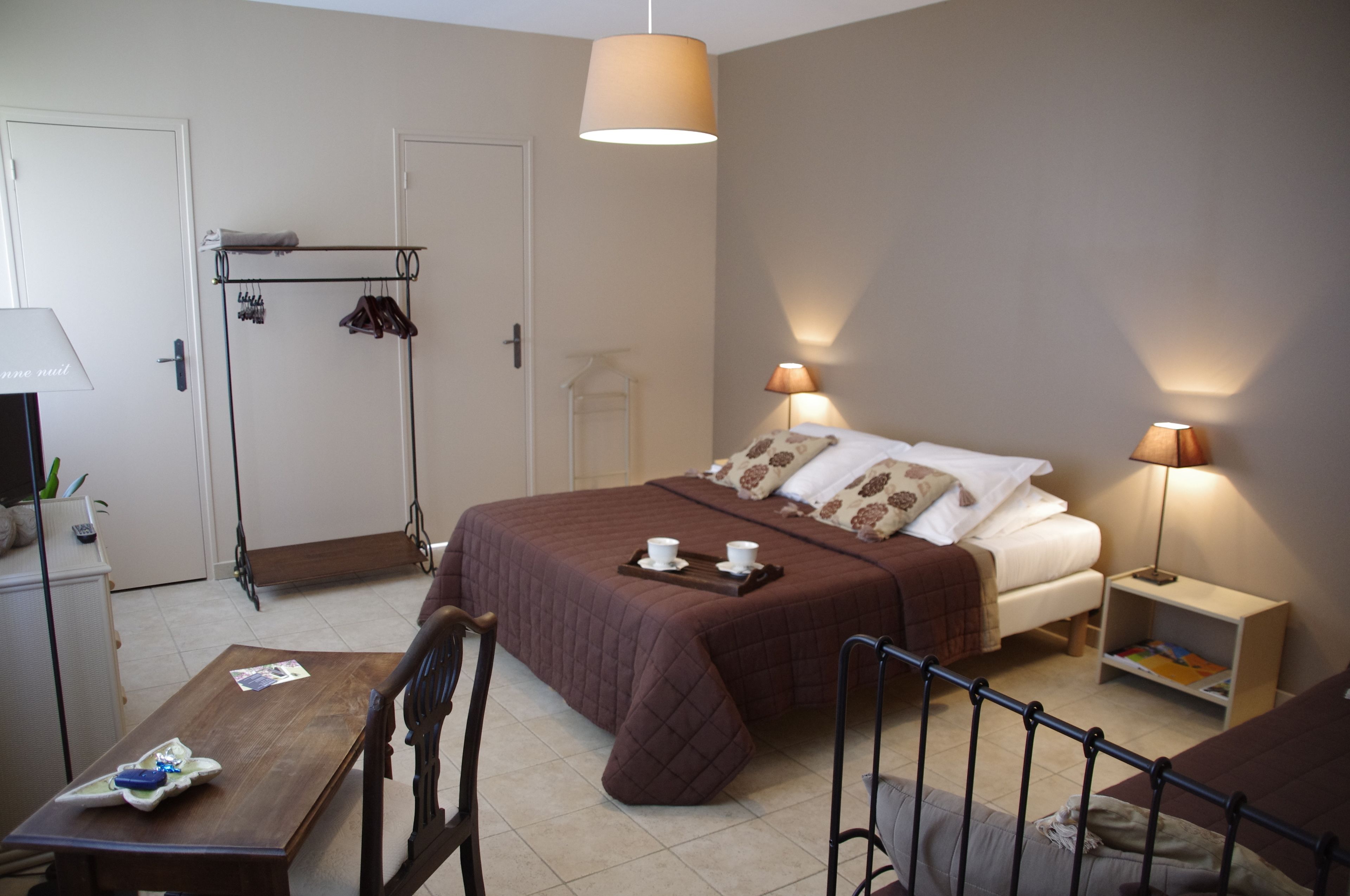 Una camera da letto ordinata con un letto, due lampade da comodino, un tavolino, una sedia e un armadio.