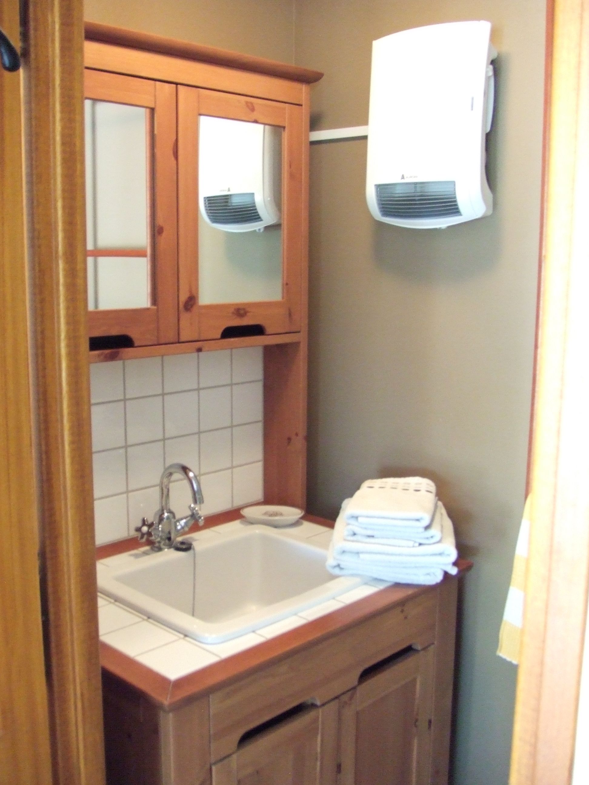 Un baño con tocador de madera, lavamanos y una pila de toallas.