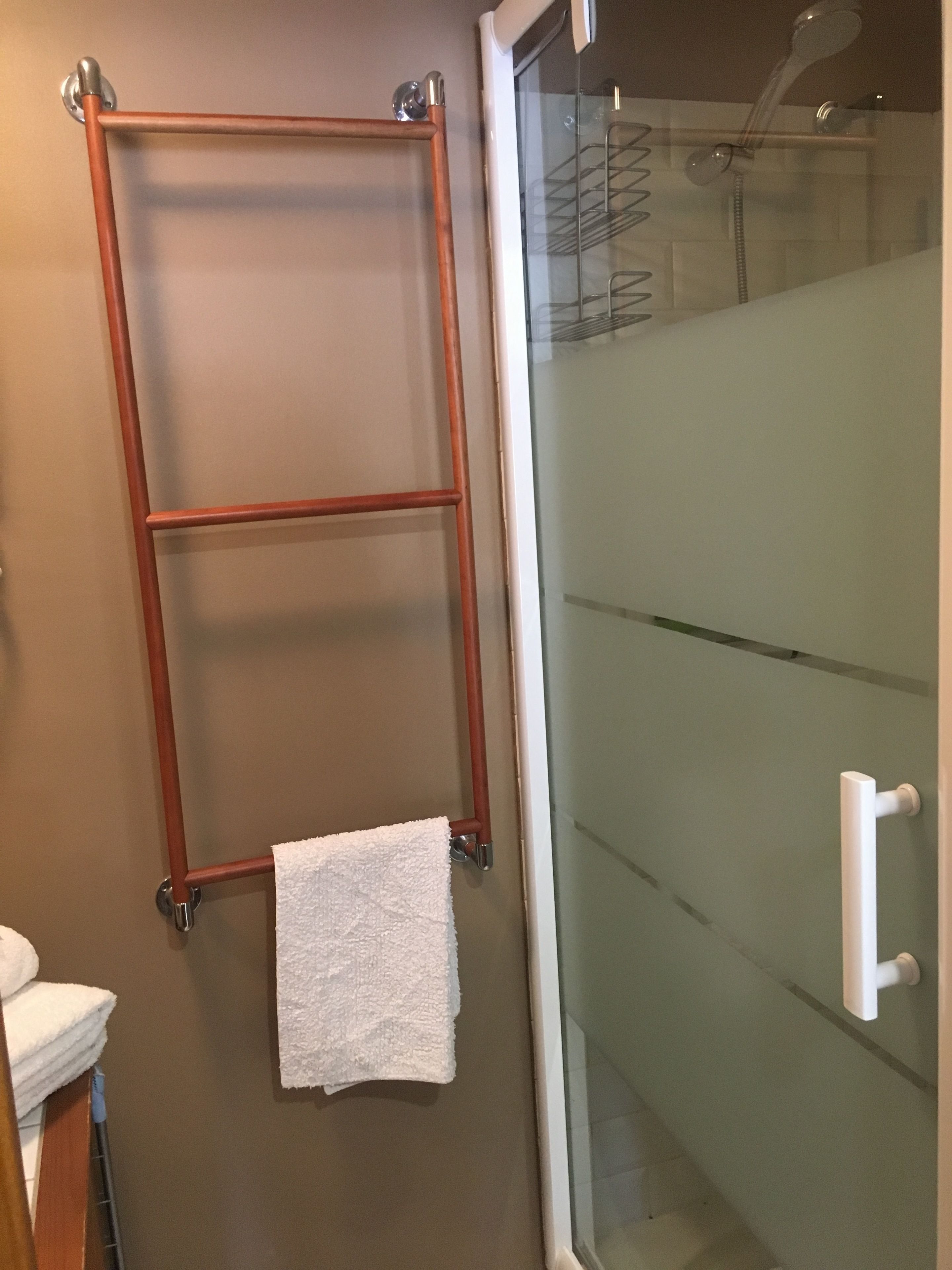 Une salle de bain avec une douche à parois de verre, un porte-serviettes en bois et une serviette blanche.
