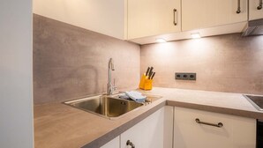 A modern kitchen with a stainless steel sink, a knife block, and a built-in oven.
