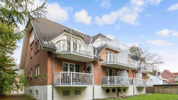 A two-story house with a brick exterior, multiple balconies, and a well-maintained lawn.