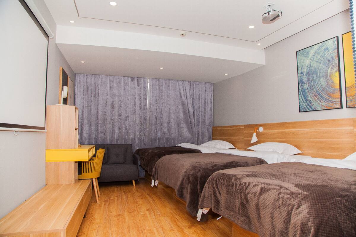 A modern hotel room with two beds, a desk, and a chair.